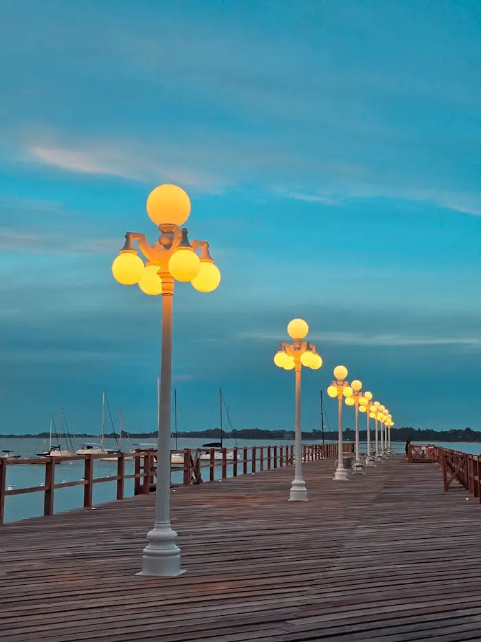 Scenic view of Colonia del Sacramento harbor at twilight with illuminated lamps on the wooden pier.
