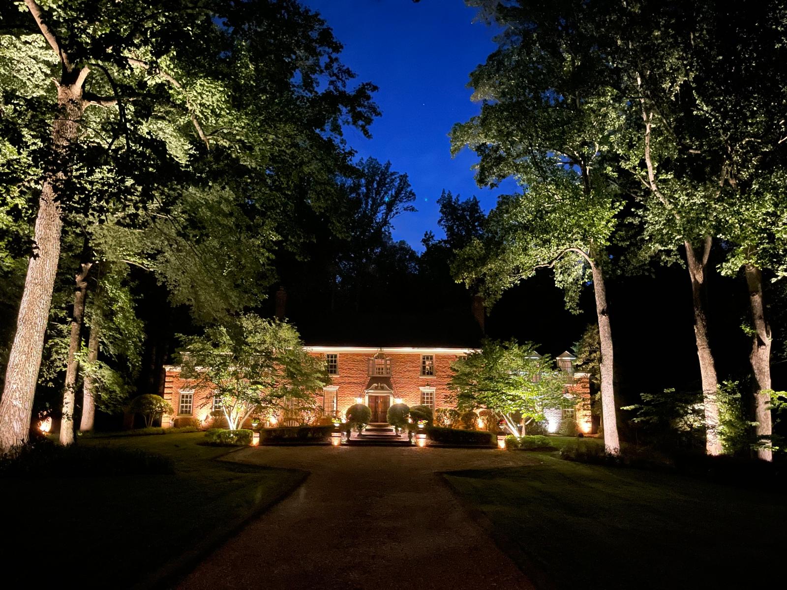 Stone home and landscape illuminated by custom outdoor lighting at night